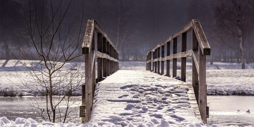 Snowy wooden bridge over mountain stream for the CFO Taskforce on SDGs - blog post