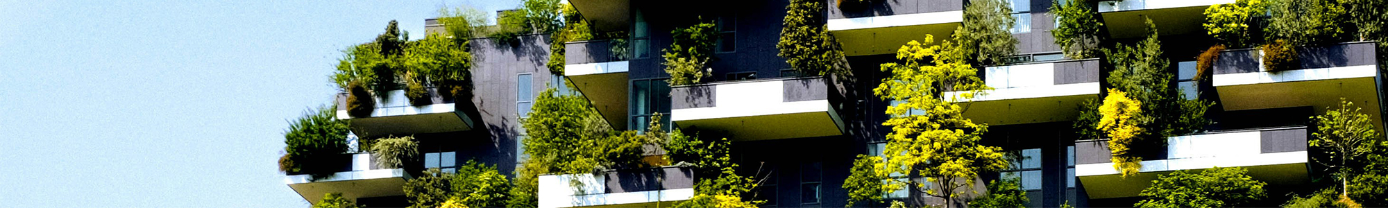 PCF-Wide Moderne Wohnungsbalkone, die dicht mit Grünpflanzen und Bäumen bewachsen sind und vor dem Hintergrund eines strahlend blauen Himmels einen üppigen vertikalen Garten bilden.