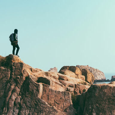 man standing on the peak of a hill